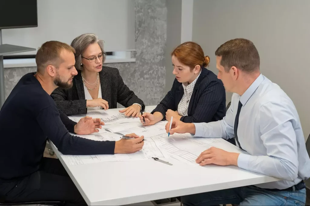 Project planning meeting: team reviewing technical drawings Team discussing project plans at a meeting table